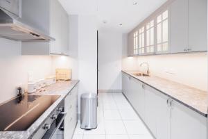 a white kitchen with white cabinets and a sink at 1001 Nights - Luxury 1-BR apartment near Burj in Dubai