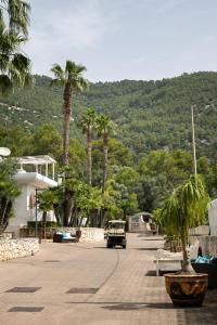 an old car driving down a street with palm trees at AH Premium Baia dei Faraglioni in Mattinata