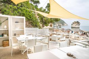 a restaurant with white tables and chairs and the ocean at AH Premium Baia dei Faraglioni in Mattinata