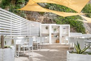 a restaurant with white chairs and tables and a yellow umbrella at AH Premium Baia dei Faraglioni in Mattinata