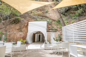 a restaurant with white tables and chairs in front of a mountain at AH Premium Baia dei Faraglioni in Mattinata