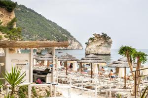 a beach with chairs and umbrellas and the ocean at AH Premium Baia dei Faraglioni in Mattinata