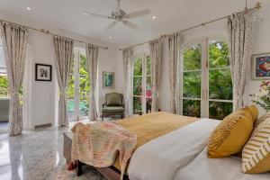 a bedroom with a large bed and large windows at La Pasado, Huge 4 BHK villa with Large Private Pool & Garden, in Assagao, Complimentary Breakfast, full time caretaker, Bathtub, ideal for large groups in Assagao