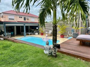 a backyard with a swimming pool and a palm tree at Villa Tropiraizet in Les Abymes