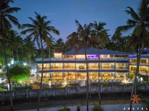a hotel at night with palm trees at Zostel Varkala in Varkala