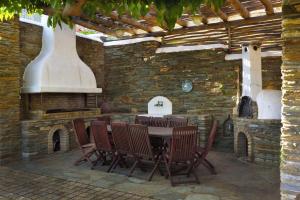 a patio with a table and chairs and a stone wall at Anastasia Luxury Villas in Gavrio