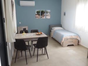 une pièce avec une table, des chaises et un lit dans l'établissement Plakopoules Beach Apartments, à Siteía