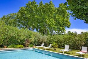 a swimming pool with chairs and a tree at Mas La Thèbaïde in Paradou
