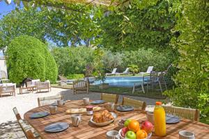 a wooden table with food on it next to a pool at Mas La Thèbaïde in Paradou +13 photos