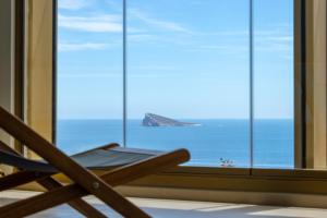 a chair in front of a window with a view of the ocean at Intempo by Holuxe - 036 - 3rd floor in Benidorm