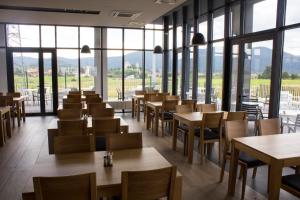 a restaurant with tables and chairs and windows at Hotel Lika Sjever in Brinje