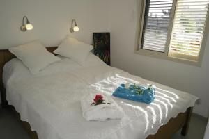 Una cama blanca con dos toallas y un bolso azul. en צימר ברחובות - Israeli Home, en Rechovot