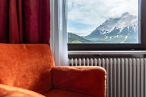 een stoel voor een raam met uitzicht op de bergen bij Pop-up Hostel - Loisach in Lermoos