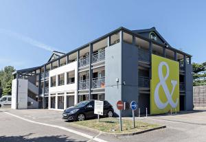 ein großes Gebäude mit Schild auf einem Parkplatz in der Unterkunft B&B HOTEL Rouen Parc des Expos Zénith in Le Grand-Quevilly