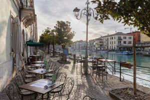 an outdoor cafe with tables and chairs next to a river at Residenza Venezia Amè in Peschiera del Garda