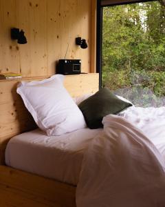 une chambre avec un lit avec des oreillers blancs et une fenêtre dans l'établissement Parcel Tiny House Brosse 1, pleine nature proche de Sancerre, à La Celle-sous-Gouzon