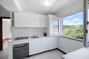 a kitchen with white cabinets and a large window at Villa Zafferano Suites - Origano in Celle Ligure +22 photos