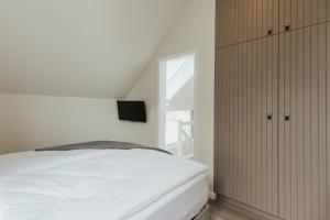 a bedroom with a white bed and a window at NEU "Rügen Resørt Sagard" großzügige, gemütliche Doppelhaushälfte "Anders" mit Terrasse in Sagard