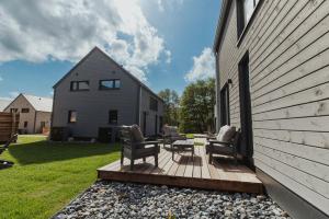 a deck with chairs and a table on a house at NEU "Rügen Resørt Sagard" großzügige, gemütliche Doppelhaushälfte "Dag" mit Terrasse in Sagard