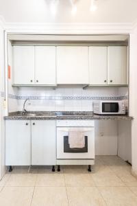 a kitchen with white cabinets and a microwave at Zafiro Calpe by Concept Flats in Ifach