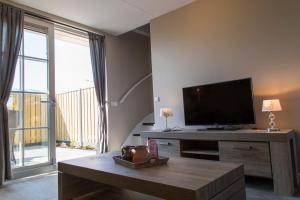 a living room with a flat screen tv and a table at Vakantiewoning aan Zee in Zoutelande