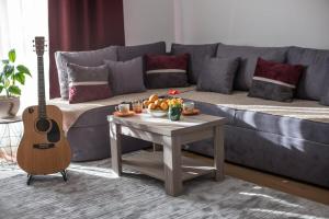 a living room with a couch with a table and a guitar at NIDA Apartment in Ulcinj