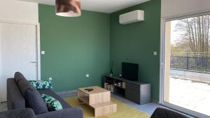 a living room with a couch and a tv at Appartement avec terrasse, proche des 1000 étangs, chapelle Le Corbusier in Roye
