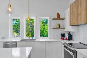 a white kitchen with white cabinets and three windows at Wellness Retreat in the Tremblant Area in La Conception