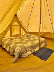 a bed in a tent with a blanket in it at Giant Canvas Rental Tent Agro-turismo Quinta da Fonte in Figueiró dos Vinhos
