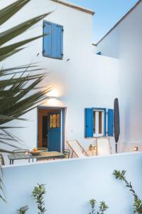 Una vista de una casa con puertas azules y una mesa. en Daphni Premium Apartment - Peaceful Veranda Stay in Tinos Old Town, en Tinos