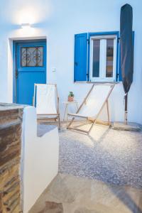 Una habitación con dos sillas y una puerta azul. en Daphni Premium Apartment - Peaceful Veranda Stay in Tinos Old Town, en Tinos