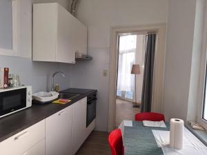 Una cocina con gabinetes blancos y una silla roja. en Midi Gateway, en Bruselas