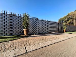a fence with two palm trees in front of it at OR Tambo Stay Unit 3 in Boksburg