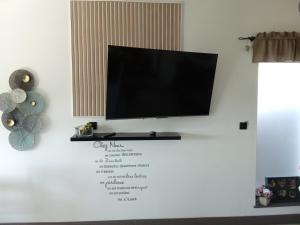 a flat screen tv hanging on a white wall at AU PETIT BONHEUR Chez l'habitant 2PERS in Ferques