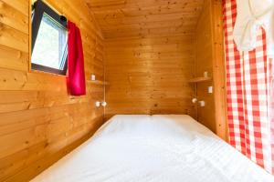a bed in a wooden cabin with a window at Tiny House in Auriac-du-Périgord