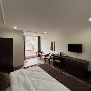 a hotel room with a bed and a desk and a television at The Ethenzong in Gangtok