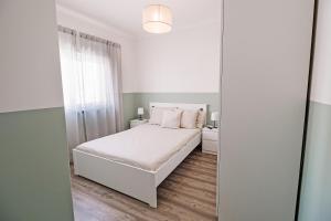 a white bedroom with a white bed and a mirror at Casa Foros de Amora in Amora