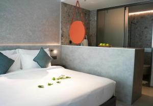 a bedroom with a large white bed with leaves on it at Sunshine Beach Residence Resort in Phuket Town +3 photos