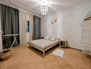 Un dormitorio con una cama y una lámpara de araña. en City Escape Assilah 1, en Asilah
