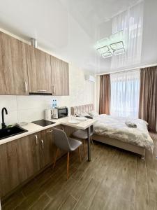 a bedroom with a bed and a table and a kitchen at Апартаменты возле метро НАУЧНАЯ in Kharkiv