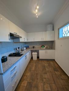 cocina con armarios blancos y suelo de madera en City Escape Assilah 1, en Asilah