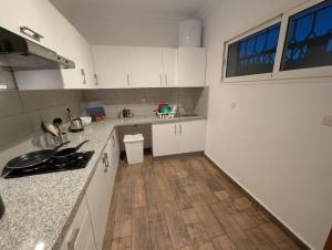 cocina con armarios blancos y suelo de madera en City Escape Assilah 1, en Asilah 2 fotos más