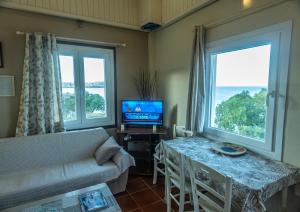 a living room with a couch and a tv and two windows at Aegean Bliss Residences - Karfas in Karfas