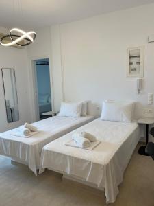 two beds in a white room with towels on them at Aeolian Breeze 3 in Tinos