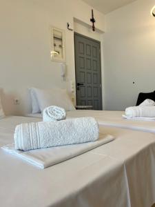 two beds with white sheets and a cross on top at Aeolian Breeze 3 in Tinos +8 photos