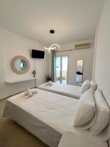 a large white bedroom with two beds and a mirror at Aeolian Breeze 3 in Tinos