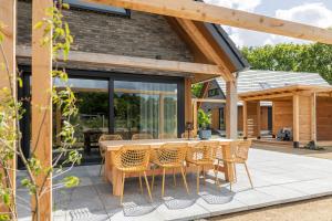 a patio with a wooden table and chairs at Luxe villa aan golfbaan en bosrand in Appelscha in Appelscha