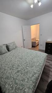 a bedroom with a large bed with a green blanket at London City Airport home 4 U in London
