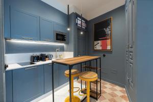 a kitchen with blue cabinets and a table and stools at Marino Marina - Unique & Exclusive Stay - Prime Location in Málaga +46 photos