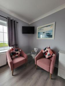 a living room with two chairs and a tv at Ashbury House - Room Only in Keel